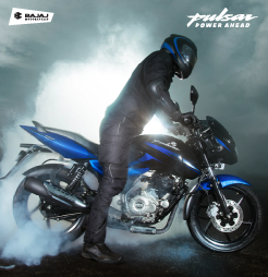 A rider in black gear performing a burnout on a blue Bajaj Pulsar 150.