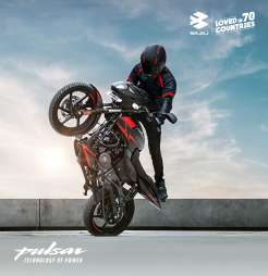 A man performs a trick on a black and red Bajaj Pulsar 150 motorcycle, showcasing his skills and balance.