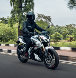 Pulsar N160  bike in blue parked against a modern backdrop, with a helmeted rider in the foreground